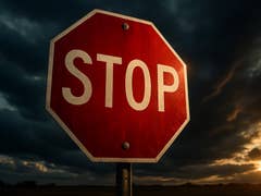 Red octagonal stop sign against a dark cloudy sky.