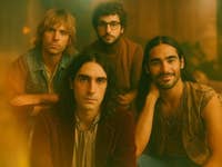 Band portrait of four musicians, featuring a warm, vintage aesthetic.