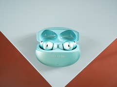 A pair of OnePlus Buds 4 inside their charging case, displayed on a light surface.