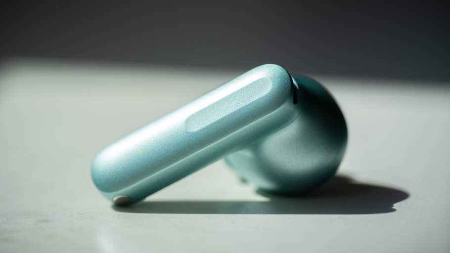 A close-up of the OnePlus Buds 4 in Zen Green on a white surface.