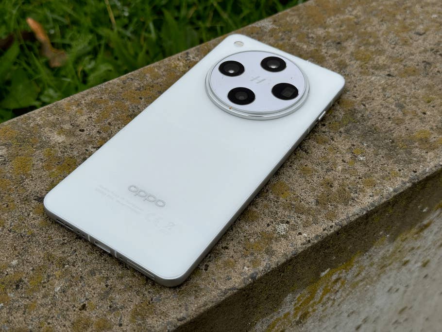 A white Oppo Find X8 Pro smartphone lies on a stone surface and shows its camera design.