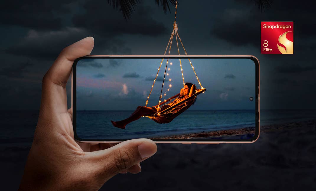 A hand holding a smartphone displaying a person swinging with lights on a beach at night, tagged 