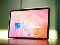 Samsung Galaxy Tab S11 displaying a colorful app interface on a wooden table.
