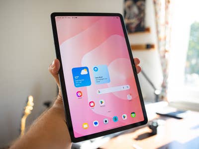 A person holds a Samsung Galaxy Tab S11 displaying a colorful home screen.
