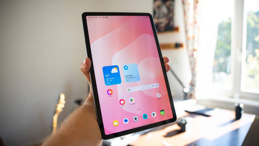 A person holds a Samsung Galaxy Tab S11 displaying a colorful home screen.
