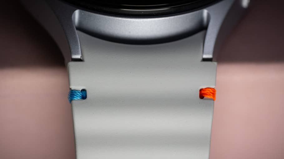 Close-up of the Samsung Galaxy Watch 7 with a grey strap and blue and orange accents.