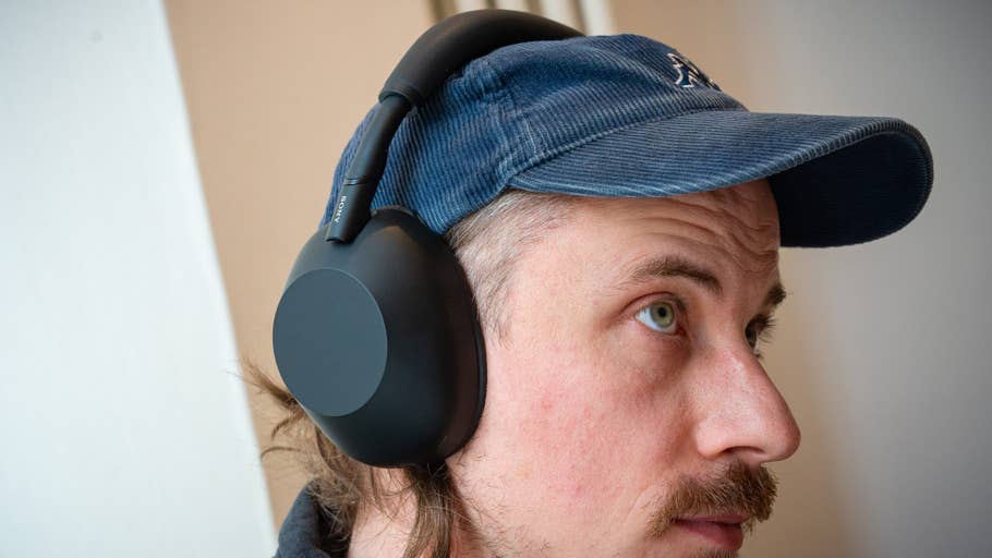 A person wearing Sony WH-1000XM6 headphones and a blue cap and looking to the side.