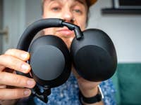 A person holding Sony WH-1000XM6 headphones, showing the ear cups and headband.