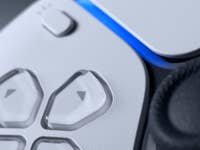 Close-up of a Sony gaming controller featuring buttons and a glowing blue light.