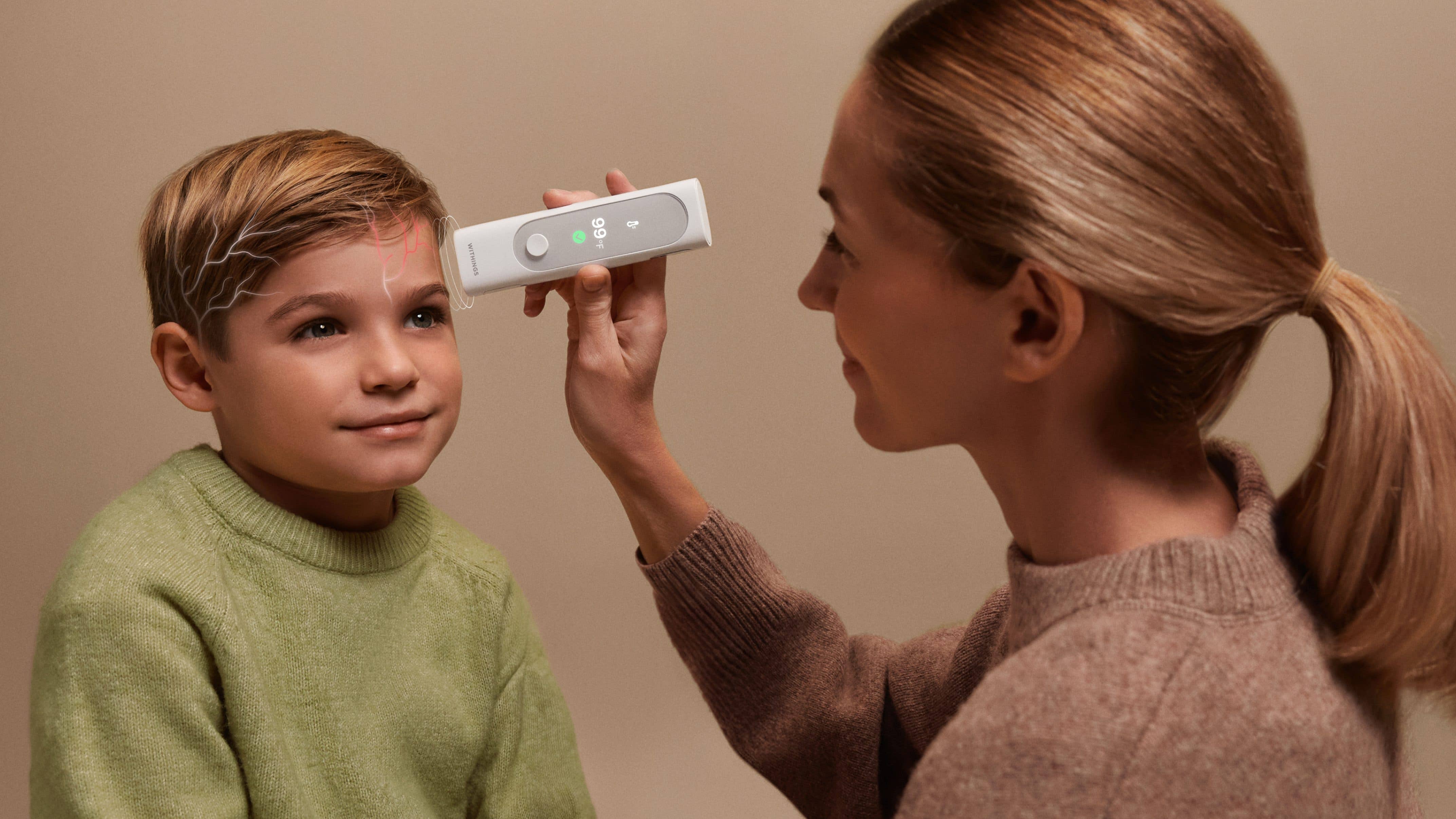 A mother measuring a child's temperature with the Withings BeamO A mother measuring a child's temperature with the Withings BeamO