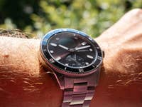 A close-up of a Withings ScanWatch Nova on a wrist with hair and sunlight in the background.