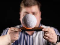 A man holds a Xiaomi phone on top of which there is a floating ball